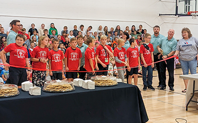 Student tellers and FirstBank of Nebraska staff prepared to cut the ribbon for the grand opening of a new in-school savings bank at St. Wenceslaus in Wahoo.